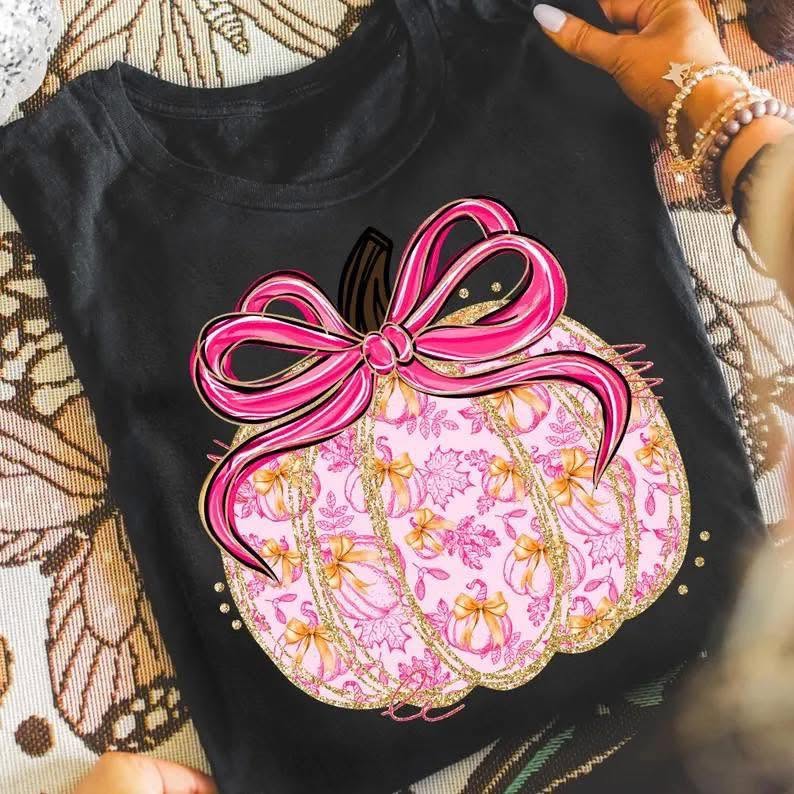 Pink and gold pumpkin with satin-style bow on black shirt