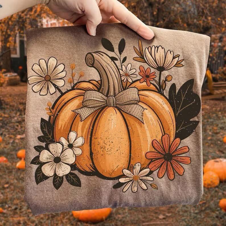 Rustic pumpkin with daisies and burlap-style bow on brown shirt