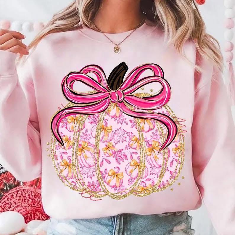 Pink and gold pumpkin with satin-style bow on pink sweatshirt