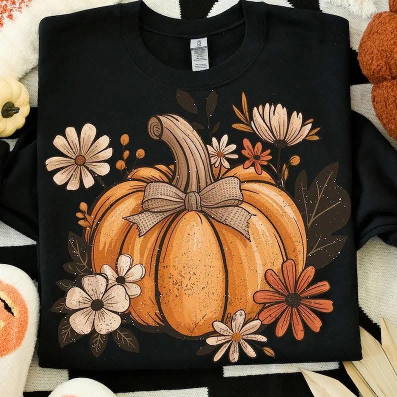 Rustic orange pumpkin with daisies and burlap-style bow on black shirt