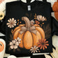 Rustic orange pumpkin with daisies and burlap-style bow on black shirt
